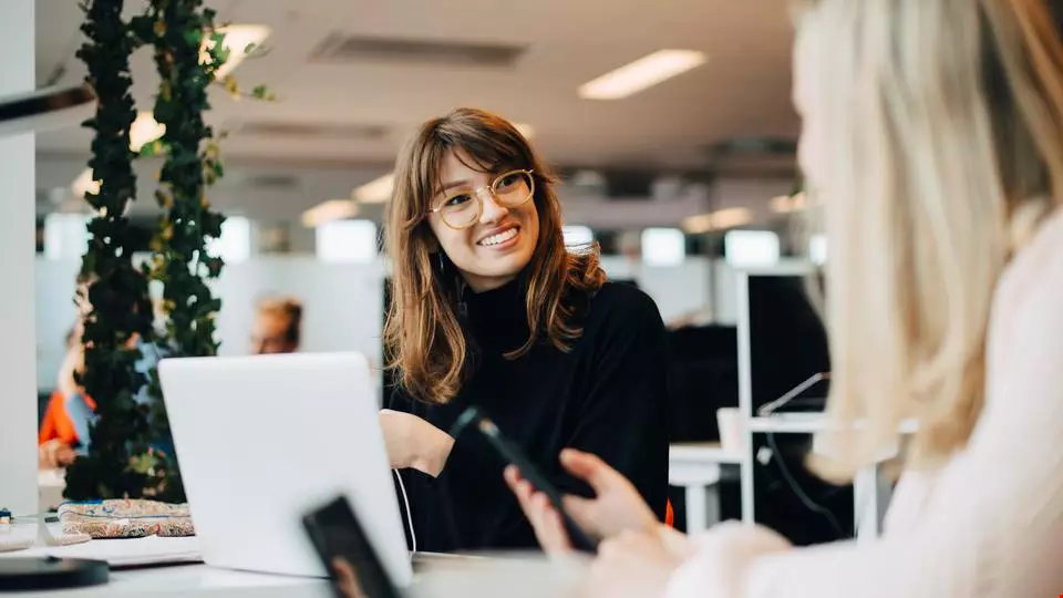 glad ung kvinna i glasögon coachar kollega i rekrytering på kontor