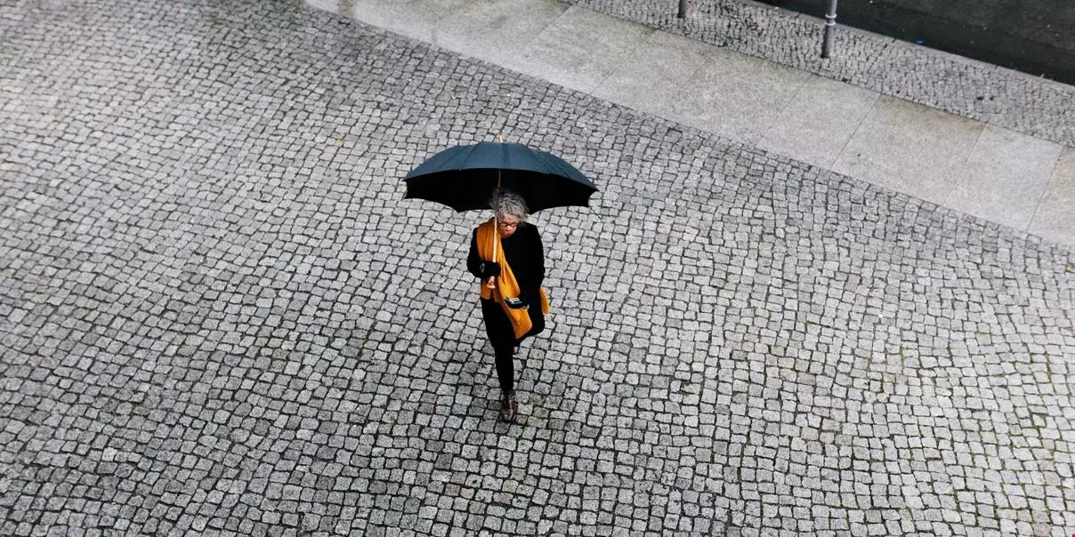 Kvinna med paraply och gul halsduk